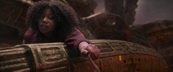 Movie still from “Transformers: Rise of the Beasts” (2023), directed by Steven Caple Jr. – A young child holding a wooden stick while sitting in a chair; Close Up shot, Over the shoulder angle