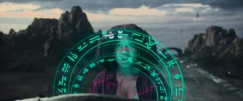 Movie still from “Transformers: Rise of the Beasts” (2023), directed by Steven Caple Jr. – A woman is looking at the camera through a circle of lights; Close Up shot, Over the shoulder angle