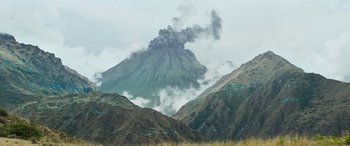Movie still from “Transformers: Rise of the Beasts” (2023), directed by Steven Caple Jr. – A mountain with a plume of smoke coming from it; Extreme Wide shot, High angle