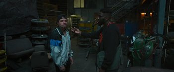 Movie still from “Transformers: Rise of the Beasts” (2023), directed by Steven Caple Jr. – Two men are talking in an industrial setting; Medium shot, Over the shoulder angle