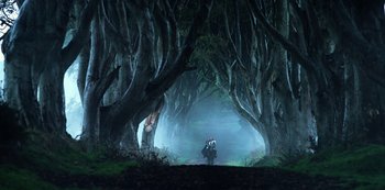 Movie still from “Transformers: The Last Knight” (2017), directed by Michael Bay – A person riding a motorcycle through a forest; Extreme Wide shot, Low angle