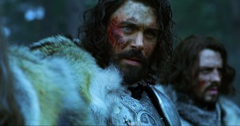 Movie still from “Transformers: The Last Knight” (2017), directed by Michael Bay – A person with a beard wearing a costume; Close Up shot, Low angle