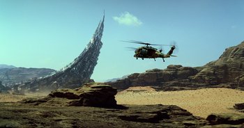 Movie still from “Transformers: The Last Knight” (2017), directed by Michael Bay – A helicopter flying over a rock formation near a tall building; Extreme Wide shot, Low angle
