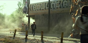 Movie still from “Transformers: The Last Knight” (2017), directed by Michael Bay – A man running down the street in front of a building; Extreme Wide shot, Low angle