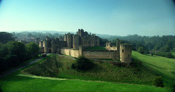 Movie still from “Transformers: The Last Knight” (2017), directed by Michael Bay – An old castle is shown in the middle of a green field; Extreme Wide shot, High angle