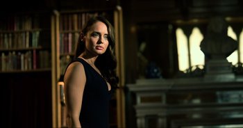 Movie still from “Transformers: The Last Knight” (2017), directed by Michael Bay – A woman in a black dress standing in front of a book case; Close Up shot, Low angle