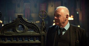 An older man standing next to an ornate cross