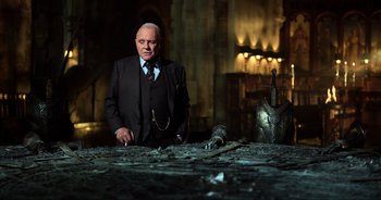 Movie still from “Transformers: The Last Knight” (2017), directed by Michael Bay – An older man standing in front of an iron helmet; Medium shot, Low angle