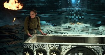 Movie still from “Transformers: The Last Knight” (2017), directed by Michael Bay – A woman standing next to a large object in a room; Medium shot, High angle