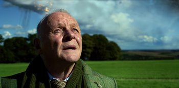 Movie still from “Transformers: The Last Knight” (2017), directed by Michael Bay – An older man in a green jacket looking up at the sky; Close Up shot, Low angle