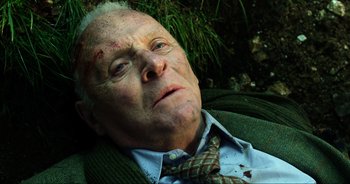 Movie still from “Transformers: The Last Knight” (2017), directed by Michael Bay – An old man laying on the ground in a field; Close Up shot, Overhead angle