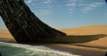 Movie still from “Transformers: The Last Knight” (2017), directed by Michael Bay – A large piece of wreckage of a ship on the beach; Extreme Wide shot, Low angle