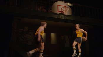 Movie still from “Trevor: The Musical” (2022), directed by Robin Abrams – Two young men are playing basketball on a court; Wide shot, Over the shoulder angle