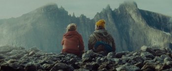 Movie still from “Troll” (2022), directed by Roar Uthaug – A man and a woman sitting on top of a mountain; Wide shot, Low angle