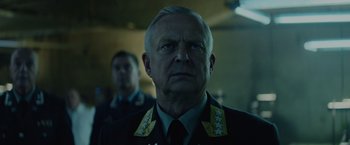 Movie still from “Troll” (2022), directed by Roar Uthaug – An older man wearing a military uniform looking at the camera; Close Up shot, Low angle