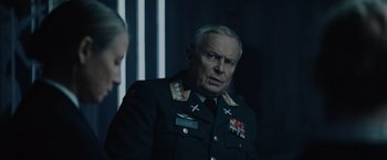 Movie still from “Troll” (2022), directed by Roar Uthaug – An older man in a military uniform looking at the camera; Medium shot, Over the shoulder angle