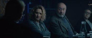 Movie still from “Troll” (2022), directed by Roar Uthaug – A man and a woman sitting next to each other in a dark room; Medium shot, Over the shoulder angle