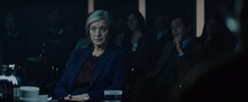 Movie still from “Troll” (2022), directed by Roar Uthaug – A woman sitting in front of a group of people; Medium shot, Over the shoulder angle
