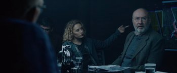 Movie still from “Troll” (2022), directed by Roar Uthaug – A woman sitting at a dinner table pointing at something; Medium shot, Over the shoulder angle