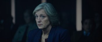 Movie still from “Troll” (2022), directed by Roar Uthaug – An older woman wearing a blue jacket and looking at the camera; Close Up shot, Over the shoulder angle