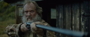 Movie still from “Troll” (2022), directed by Roar Uthaug – An old man holding a rifle and looking at the camera; Close Up shot, Low angle
