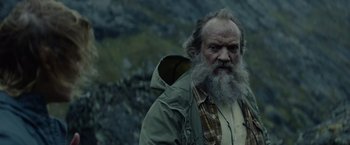 Movie still from “Troll” (2022), directed by Roar Uthaug – An old man with a beard and a jacket on; Close Up shot, Low angle