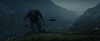 Movie still from “Troll” (2022), directed by Roar Uthaug – A helicopter flying near a giant monster in a field; Extreme Wide shot, Low angle