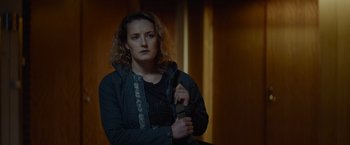 Movie still from “Troll” (2022), directed by Roar Uthaug – A woman holding a knife while standing in a dark room; Medium shot, Low angle