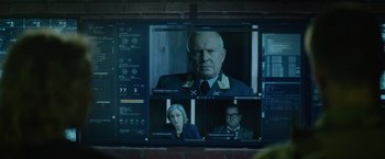 Movie still from “Troll” (2022), directed by Roar Uthaug – A television screen showing a man and two women; Close Up shot, Over the shoulder angle