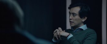 Movie still from “Troll” (2022), directed by Roar Uthaug – A man in a green shirt is holding his wrist; Close Up shot, Over the shoulder angle