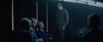 Movie still from “Troll” (2022), directed by Roar Uthaug – A group of people sitting in a dark room; Medium shot, Over the shoulder angle