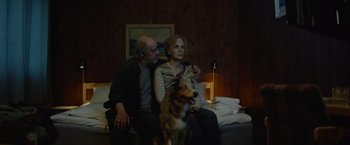 Movie still from “Troll” (2022), directed by Roar Uthaug – A man and a woman sitting next to a dog on a couch; Medium shot, High angle