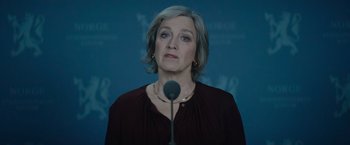 Movie still from “Troll” (2022), directed by Roar Uthaug – A woman standing in front of a microphone in a room; Close Up shot, Low angle