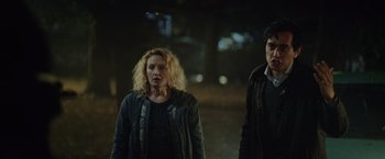 Movie still from “Troll” (2022), directed by Roar Uthaug – A woman and a man standing next to each other in the dark; Medium shot, Low angle