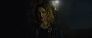 Movie still from “Troll” (2022), directed by Roar Uthaug – A woman with blonde hair is standing in the dark; Close Up shot, Over the shoulder angle