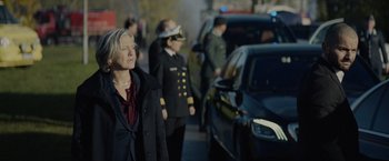 Movie still from “Troll” (2022), directed by Roar Uthaug – A group of people standing next to each other near police cars; Medium shot, Over the shoulder angle