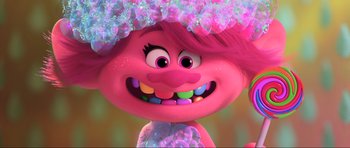 Movie still from “Trolls World Tour” (2020), directed by Walt Dohrn – A pink troll is smiling with candy in her mouth; Close Up shot, Low angle