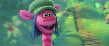 Movie still from “Trolls World Tour” (2020), directed by Walt Dohrn – A pink troll with blue hair and a green hat; Close Up shot, Low angle