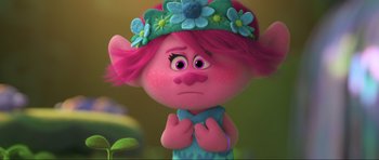 Movie still from “Trolls World Tour” (2020), directed by Walt Dohrn – A pink haired troll with a blue flower crown on her head; Close Up shot, Low angle