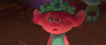 Movie still from “Trolls World Tour” (2020), directed by Walt Dohrn – A pink haired troll with a flower crown on her head; Close Up shot, Over the shoulder angle