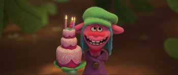 Movie still from “Trolls World Tour” (2020), directed by Walt Dohrn – A troll holding a birthday cake with two lit candles on it; Close Up shot, High angle