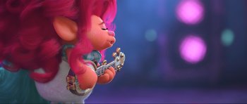 Movie still from “Trolls World Tour” (2020), directed by Walt Dohrn – A pink haired troll playing an electric guitar; Medium shot, Over the shoulder angle