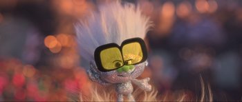 Movie still from “Trolls World Tour” (2020), directed by Walt Dohrn – A troll doll wearing glasses and a white wig; Close Up shot, Low angle