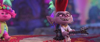 Movie still from “Trolls World Tour” (2020), directed by Walt Dohrn – A troll with a red mohawk is sitting on a chair; Medium shot, Over the shoulder angle