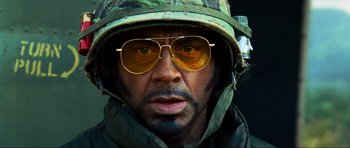 Movie still from “Tropic Thunder” (2008), directed by Ben Stiller – A man wearing a hat and sunglasses; Close Up shot, Low angle