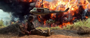 Movie still from “Tropic Thunder” (2008), directed by Ben Stiller – A man sitting on the ground in front of a helicopter; Extreme Wide shot, Low angle