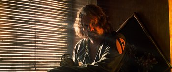 Movie still from “Tropic Thunder” (2008), directed by Ben Stiller – A man sitting in front of a window; Medium shot, Low angle