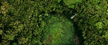 Movie still from “Tropic Thunder” (2008), directed by Ben Stiller – An aerial view of a forest with a helicopter flying over it; Extreme Wide shot, Overhead angle