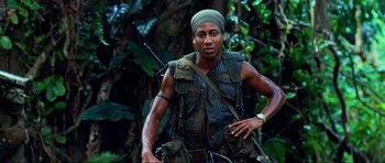 Movie still from “Tropic Thunder” (2008), directed by Ben Stiller – A man with a rifle in his hand and a backpack on; Medium shot, Low angle
