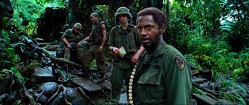 Movie still from “Tropic Thunder” (2008), directed by Ben Stiller – A group of men standing next to each other in the woods; Medium shot, Over the shoulder angle